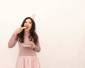young beautiful woman in a pink dress celebrates holidays and eats a cake