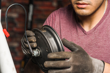 A mechanic holding a wheel rim of an electric scotter for repair