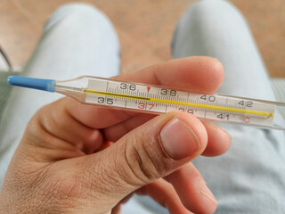 Man hold a Mercury fever thermometer after measurement,coronavirus covid19 pandemic