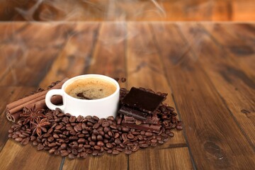 Hot coffee in a white coffee cup and many beans placed around
