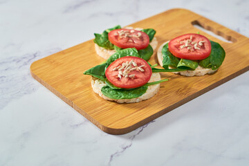Healthy snack of rice cakes with spinach and tomato on top.