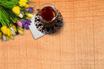 A cup of hot, morning coffee and a bouquet of tulips on a desk.
