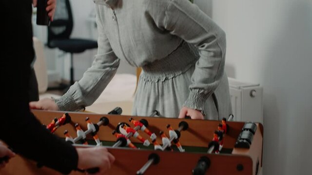 Close up of woman winning game at foosball table and having fun with workmates at office after work. Cheerful person enjoying win while having drinks after hours with entertainment
