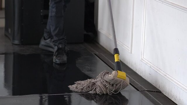 A man is mopping the floor with a mop and dancing at home, enjoying housework. People, modern lifestyle and youth concept.