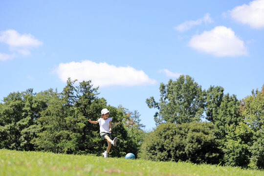 芝の上でサッカーをする女子小学生 (6歳)