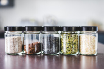 seeds including pumpkin chia sesame and flax in matching spice jars on kitchen counter, simple...