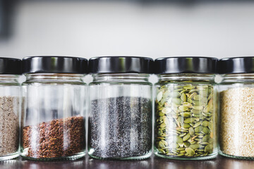 seeds including pumpkin chia sesame and flax in matching spice jars on kitchen counter, simple vegan ingredients to flavour your dishes