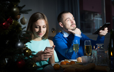 Unhappy couple celebrating New Year at home and watching TV