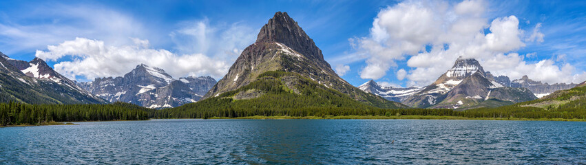 Spring at Swiftcurrent Lake - A panoramic view of Swiftcurrent Lake, with rugged mountain peaks towering at west shore, on a sunny Spring morning. Many Glacier, Glacier National Park, Montana, USA.