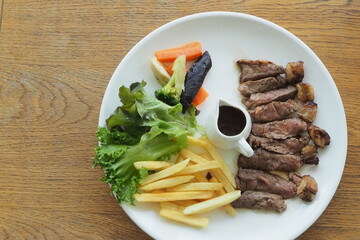 Photo grilled beef steak with french fries on disk, top view.