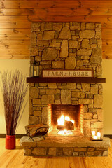 Cozy fire in a stone fireplace with a farmhouse sign, candles and reeds.