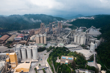 Aerial view of cement factory tower with high concrete plant structure at industrial production area. Manufacturing and global industry concept.