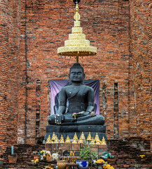 Aytthaya, Thailand, 22 Aug 2020 : Ancient Buddha statue and the wall made by old red brick background at Wat Thammikarat in The Historical Park of Ayutthaya Thailand. Selective focus.
