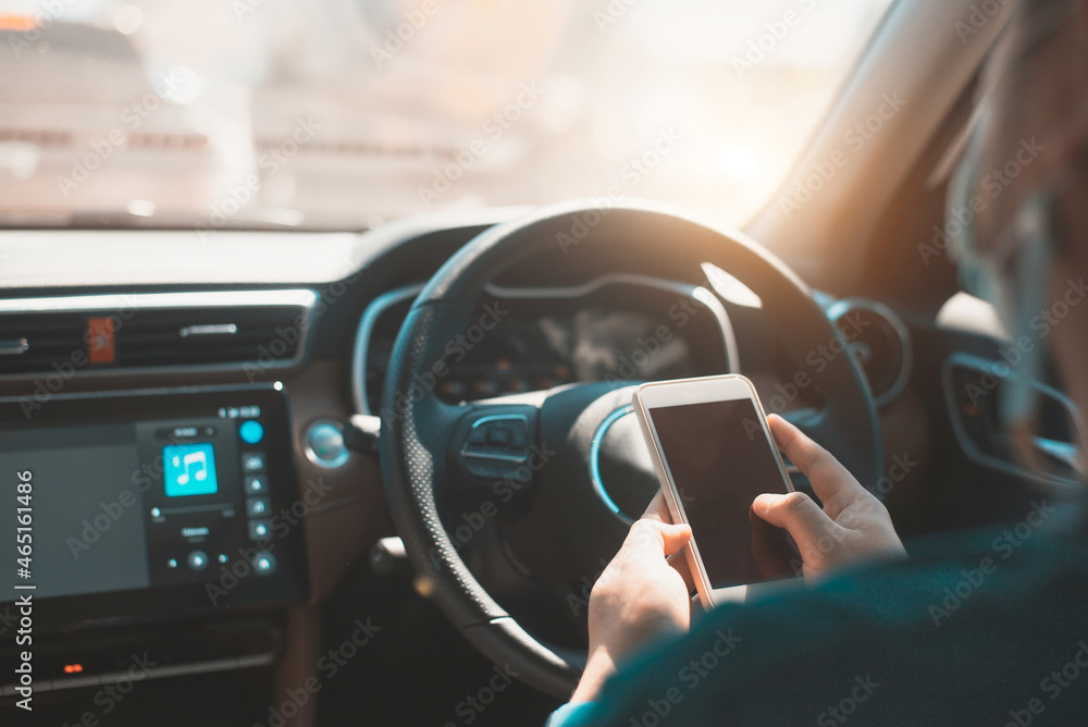 Poster man using mobile smart phone inside a car. driver hand holding blank black screen smartphone, search