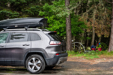 Fototapeta premium Roof rack and cargo box mounted on a vehicle with active precipitation.