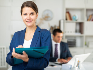Female office worker is standing with documents before signing it in office