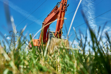 A red powerful crawler excavator standing on a grassy area. Industrial theme