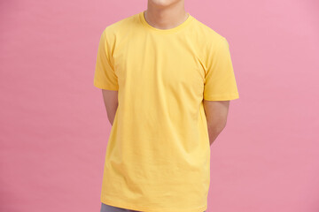 partial view of man in yellow t-shirt holding hands behind back isolated on pink