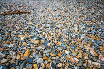 Multi-colored round rocks on Little Hunters Beach in Acadia National Park, Maine. Tide coming in as waves crash. 