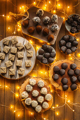 Assorted chocolate candies on wooden background with garland