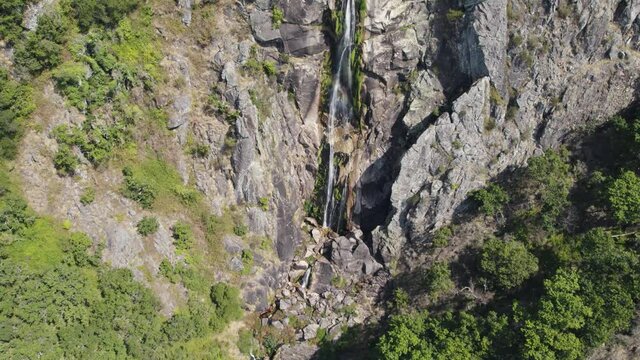 Aerial tilt up Majestic Waterfall on stone cliff, Frecha da Mizarela - Portugal