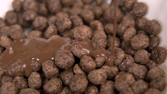 Chocolate sauce falling on choco ball cereal in a bowl - Slow motion
