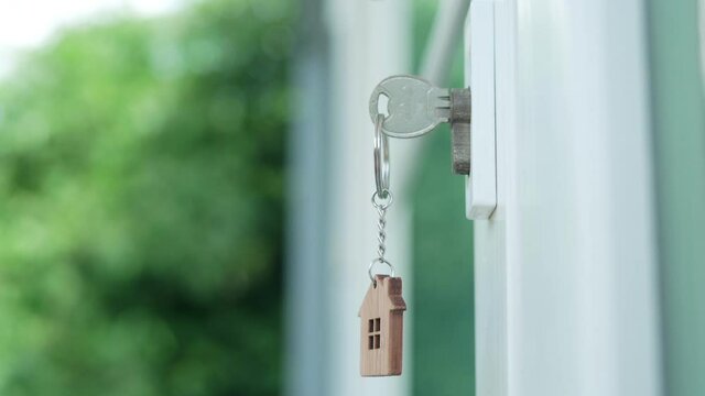 Deal contract complete. Sell your house, rent house and buy ideas. The house key for unlocking a new house is plugged into the door.The keychain is blowing in the wind.