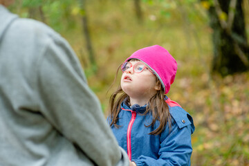 Little girl with special needs talks with her mother at autumn park