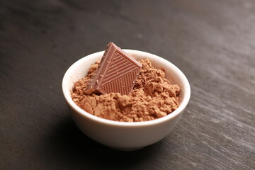 chocolate in a white cup with cocoa on a black background