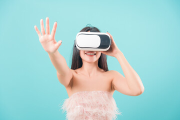 Naklejka premium Asian happy portrait beautiful young woman standing smile her using a virtual reality headset, playing on VR glasses device on blue background with copy space for text