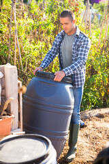 Farmer with a plastic barrel in a summer garden
