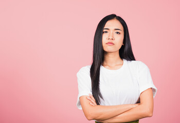 Obraz premium Asian happy portrait beautiful cute young woman standing with crossed arms angry and mad raising fist frustrated and furious while shouting with anger isolated, studio shot on pink background