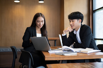 Two successful businesspeople analyzing statistical graph together on laptop computer.
