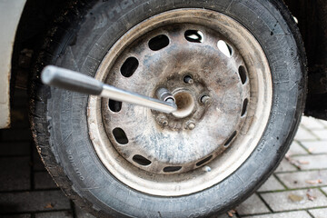 The nut of the used car wheel is screwed out with a wrench.
