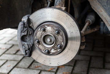 Front assembly of ventilated disc brake and wheel hub on an used car, view with removed wheel.