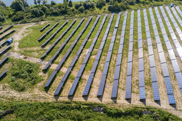 Aerial view of solar power plant on green field. Electric farm with panels for producing clean...
