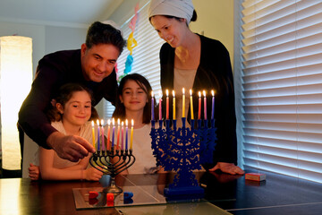Family kindling candles on the eight day of Hanukkah Jewish holiday festival