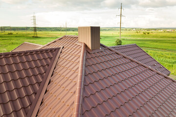 Aerial view of house roof structure covered with brown metal tile sheets.