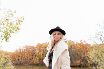 Young woman is walking by the lake in the autumn forest.