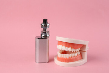 Jaw model and electronic vaping device on a pink background.