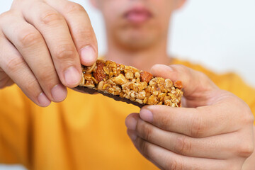 A man holding a protein bar on yellow background close-up.