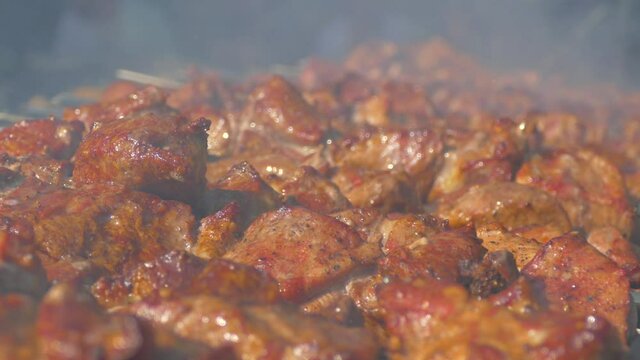 Barbecue meat on skewers pranks on the grill. Juicy pork is cooked in smoke. Meat kebab