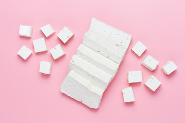 A sliced pieces and cubes of tofu on pink background close-up.