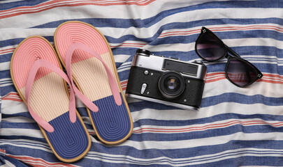 Flip flops, camera and sunglasses on a striped surface. Beach vacation concept