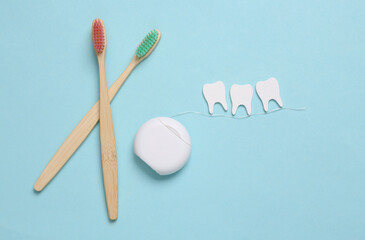 Dental care concept. Eco toothbrushes, dental floss with teeth on blue background. Top view. Flat lay