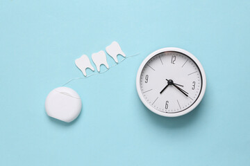 Dental care concept. Dental floss with teeth and clock on blue background. Top view. Flat lay