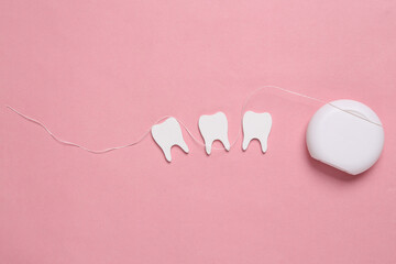 Dental care concept. Dental floss with teeth on pink background. Top view. Flat lay