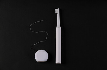 Dental care concept. Toothbrush and dental floss on black background