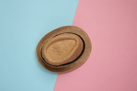 Straw hat on blue pink pastel background. Top view