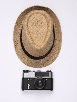 Straw hat and retro camera on white background. Top view
